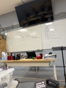 A whiteboard displaying electrical diagrams for GFCI and circuit breakers, used for training at Escuela Tecnica ABC in North Chicago, IL