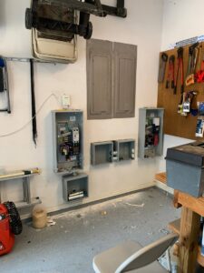 An electrical installation in progress on a garage wall, showing open electrical boxes and conduits by Volta Electrical LLC in Plano, TX.