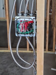 An open electrical junction box with wires and flexible conduit installed by FOXX & Hounds Electric in Sioux City, IA.