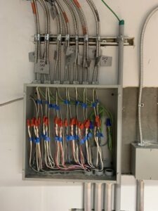 An open electrical junction box showing neatly wired connections and conduits, completed by P&E Electric in Denver, CO.