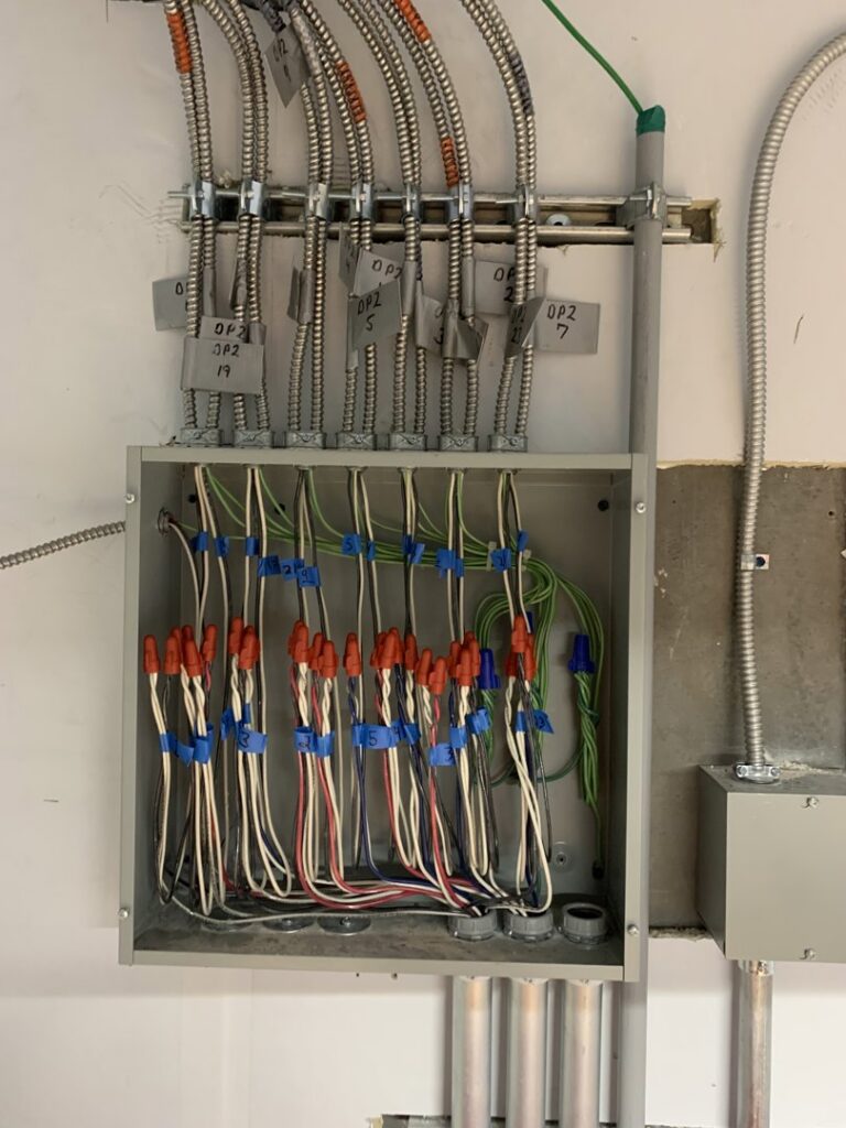 An open electrical junction box showing neatly wired connections and conduits, completed by P&E Electric in Denver, CO.
