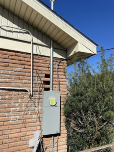 An electrical meter box and conduit installed on the exterior of a brick house by Savoski's Electrical & AC, LLC in Sunset, LA