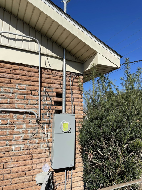 An electrical meter box and conduit installed on the exterior of a brick house by Savoski's Electrical & AC, LLC in Sunset, LA