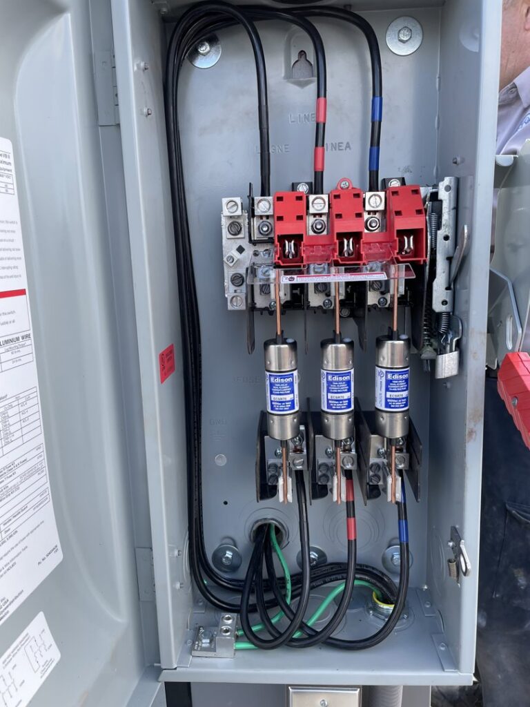 An open electrical meter box showing fuses and heavy-gauge wiring, serviced by Big Red Electric Company in San Antonio, TX.