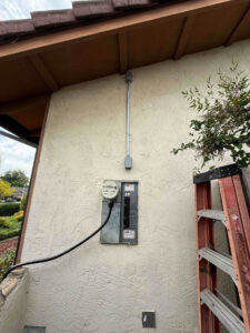 A newly installed electrical meter and conduit on the exterior of a home, with a ladder nearby, by AAA Electrical Services in Sacramento, CA.