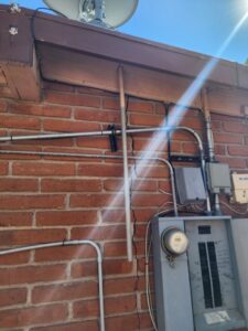 An electrical meter and service panel with conduit installed on a brick wall by CDB Electrical LLC in Tucson, AZ.