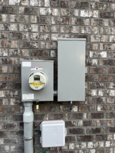 An exterior electrical meter and service panel installed on a brick wall by Shocking Solutions in Knoxville, TN.