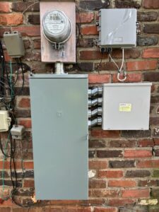 An outdoor electrical meter and service panel installed on a brick wall by Top Tier Electrical Services LLC in Knoxville, TN