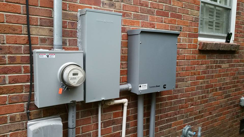 An electrical meter and Cummins Onan transfer switch installed on a brick wall by Stone Electrical Construction in Florence, SC.