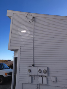 Multiple electrical meters and conduits installed on the side of a building by Lindquist Electric in Upton, MA.