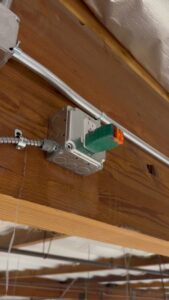 An electrical outlet and conduit installed on a wooden beam, demonstrating wiring work by CLB Electric Corporation in Norwalk, CA