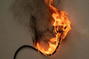 An electrical outlet and cord on fire, indicating a serious hazard that Square Electrical LLC in Alexandria, VA can safely repair.