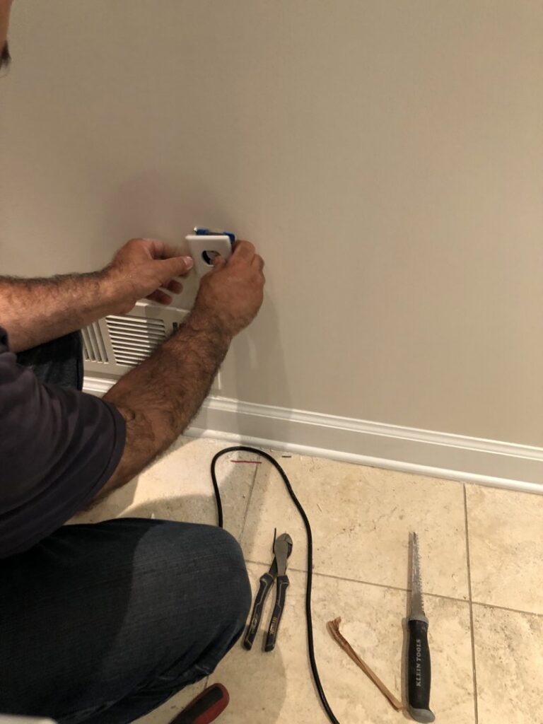 An electrician installing an electrical outlet on a wall for Detroit Voltage in Detroit, MI.