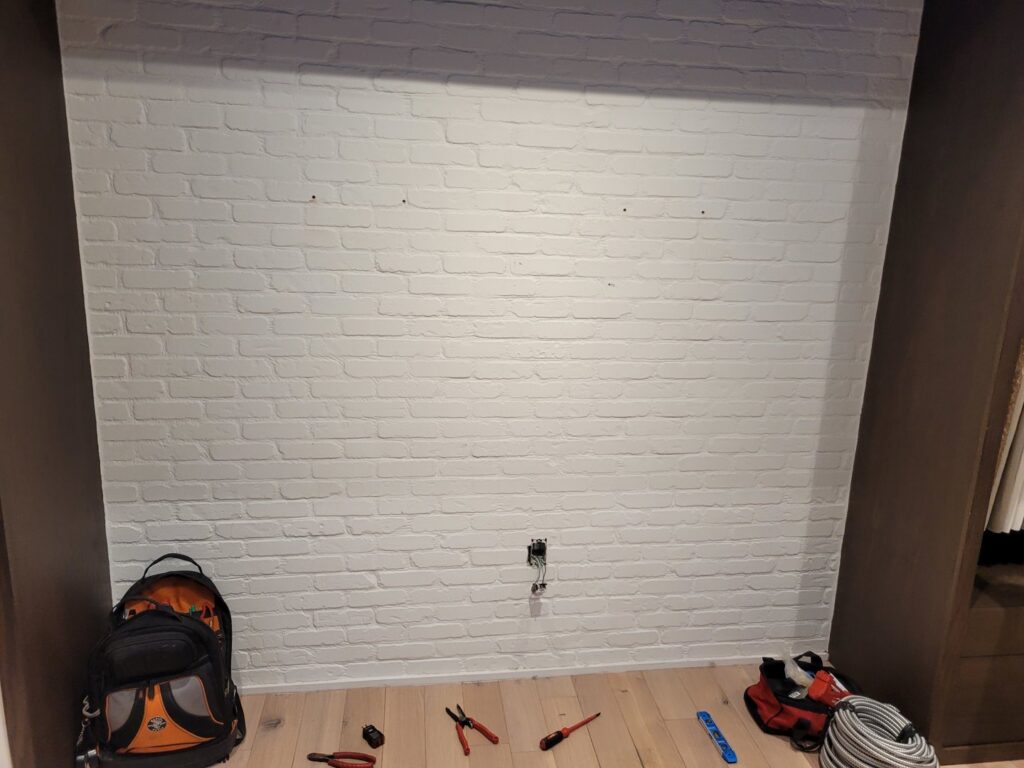 An electrical outlet being installed on a brick wall with tools on the floor by KS Retail Solutions in Victoria, TX