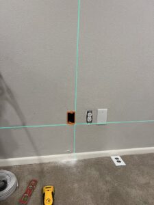 Preparation for new electrical outlet installation with a laser level by Sparrow Electric, LLC in Denver, CO.