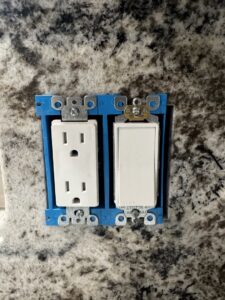 An electrical outlet and light switch being installed in a blue box by kt_electricalcontractors in Spokane Valley, WA