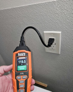 An electrician performing an electrical outlet test with a Klein Tools device, showing correct wiring by Bee Thumb Electric in North Highlands, CA.
