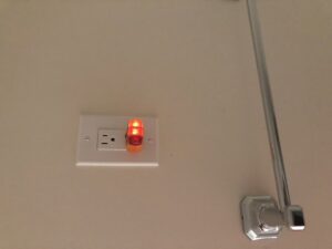 An electrician from Farris Electric LLC testing an electrical outlet with a plug-in tester in Glendale, AZ.