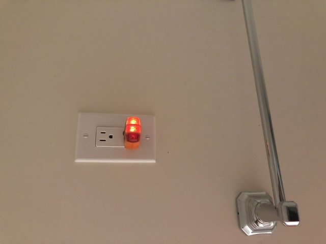 An electrician from Farris Electric LLC testing an electrical outlet with a plug-in tester in Glendale, AZ.