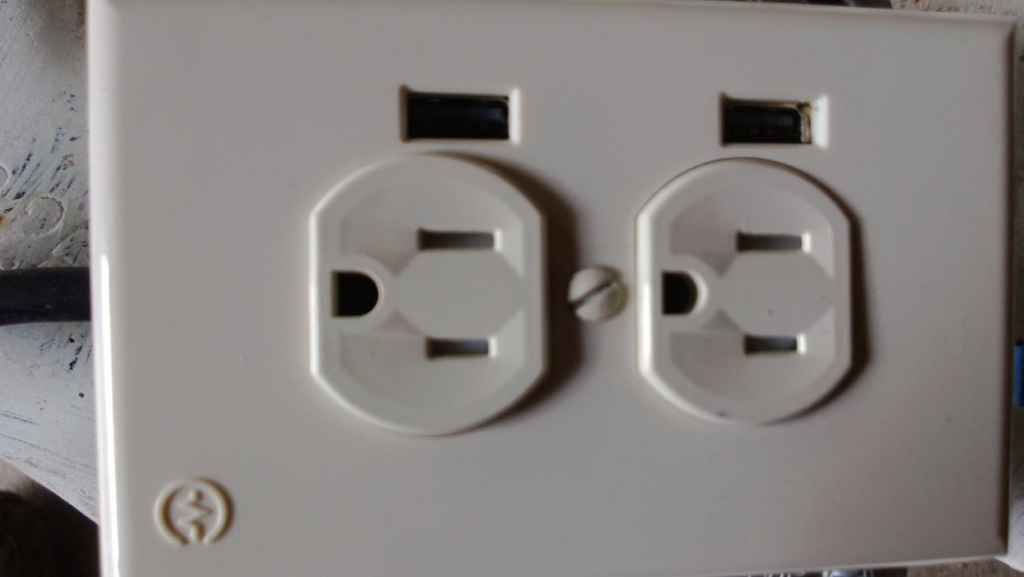 A modern electrical outlet featuring two standard receptacles and two USB charging ports, installed by Dearinger Electric in Wichita, KS.