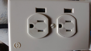 A modern electrical outlet featuring two standard receptacles and two USB charging ports, installed by Dearinger Electric in Wichita, KS.