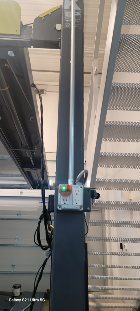 Close-up of electrical outlets and conduit installed on a car lift by Kross Homes & Security in Dallas, TX