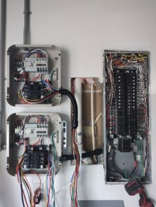 Complex electrical panel and transfer switch installation with exposed wiring, demonstrating expert work by Envision Electrical Solutions in Fort Lauderdale, FL.