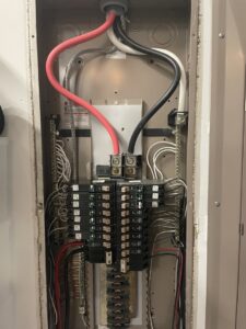 An open electrical panel (breaker box) with wiring by Clarity Handyman Service in Raleigh, NC