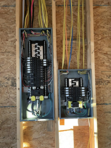 Two electrical panels with wiring and circuit breakers installed during rough-in by Leggett Electric LLC in Jackson, TN.