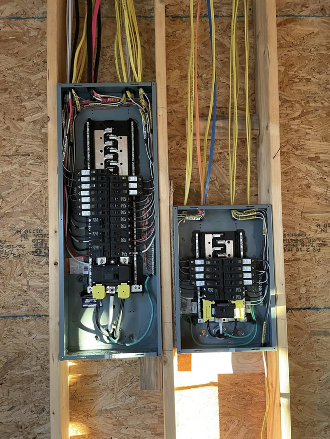 Two electrical panels with wiring and circuit breakers installed during rough-in by Leggett Electric LLC in Jackson, TN.