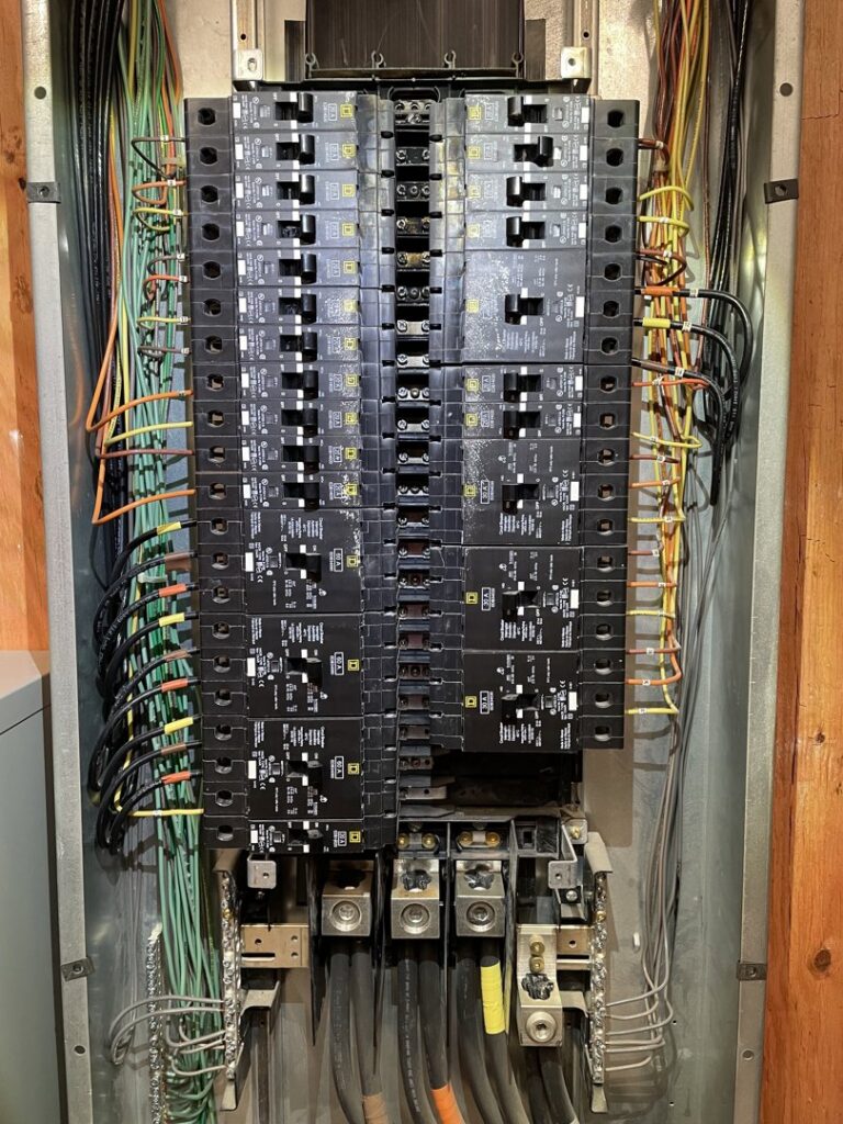 An open electrical panel with circuit breakers and wiring by Onsite Electrical Services in Raleigh, NC.