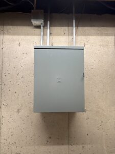 A closed electrical panel with conduit installed on a concrete wall by Swartz Electric in Colorado Springs, CO.