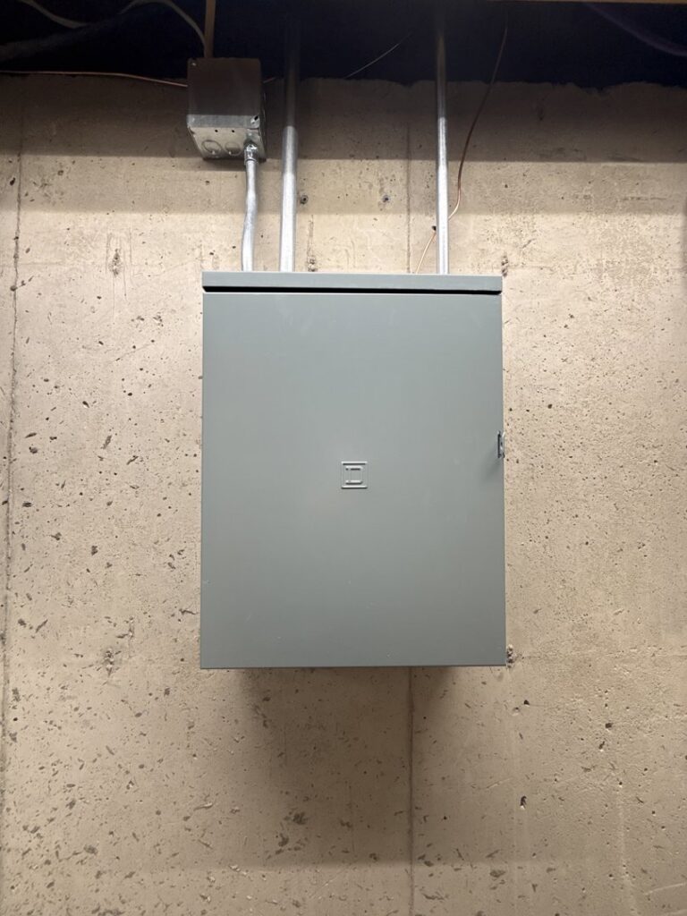 A closed electrical panel with conduit installed on a concrete wall by Swartz Electric in Colorado Springs, CO.