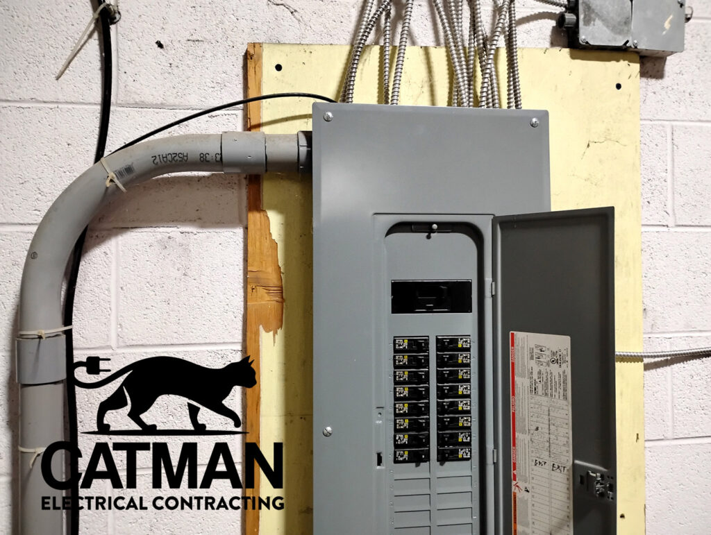 An electrical panel with conduit entering from the top, showing breakers, installed by Catman Electrical Contracting in Dallas, PA.