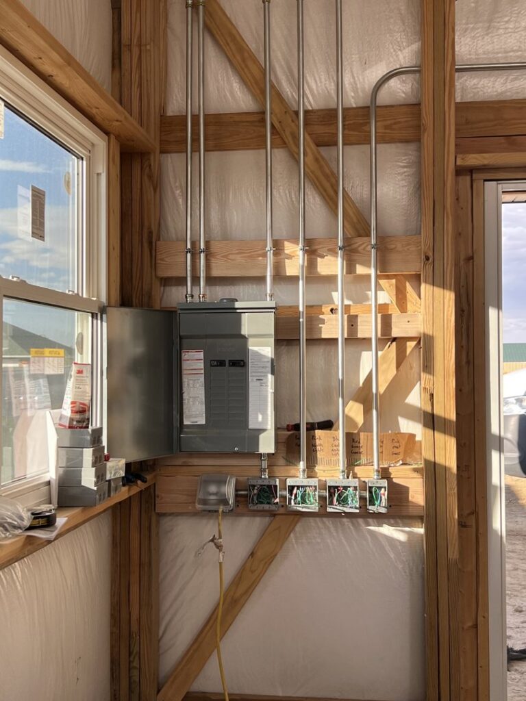 An electrical panel and conduit installation on a wooden wall by P.H. Electric in Soulsbyville, CA.