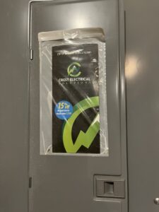 An electrical panel with a Crest Electrical Solutions flyer and discount offer attached, indicating recent service in Arlington, TX.
