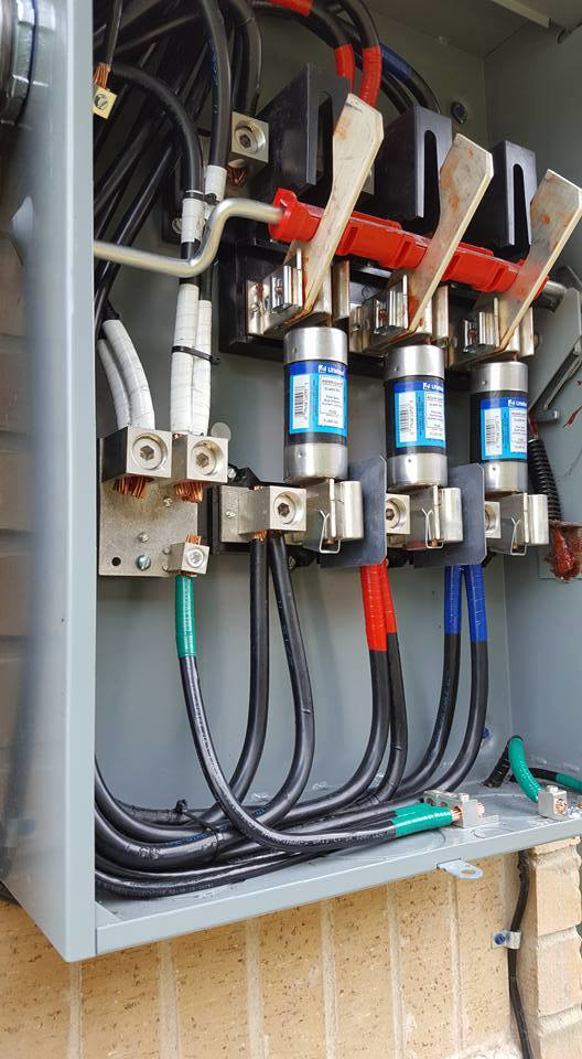 A close-up view of an open electrical panel showing fuses and heavy-gauge wiring by Genesys Electrical Contractors in Dallas, TX