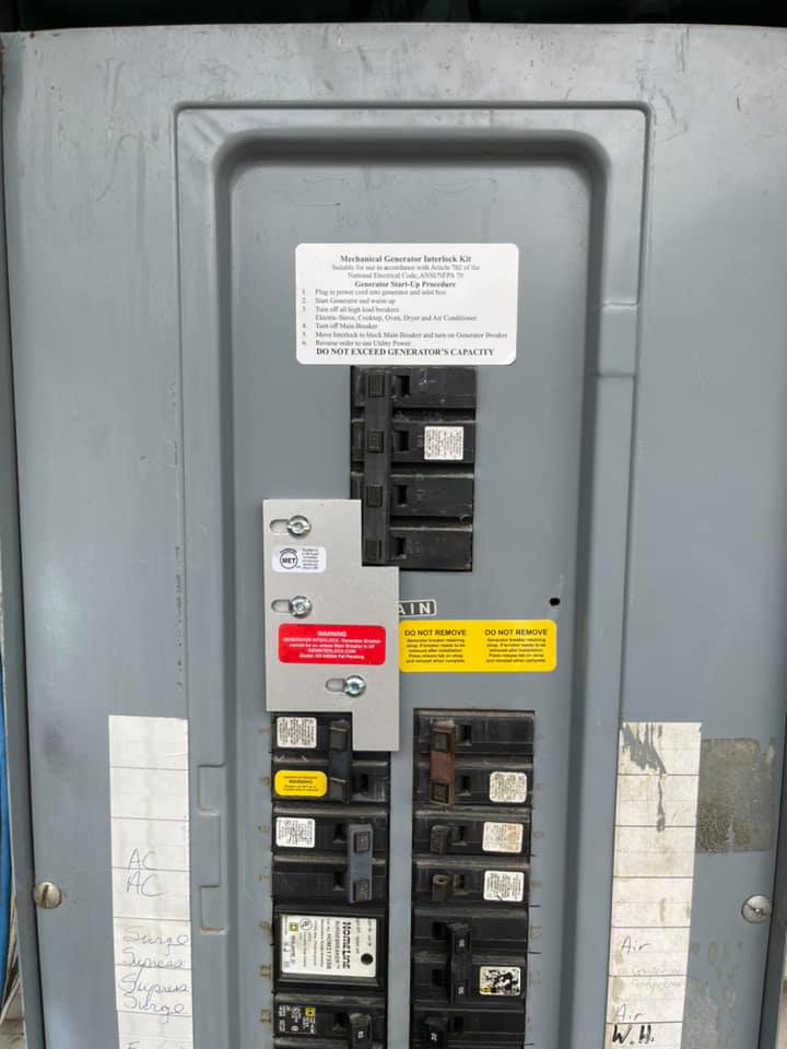 An open electrical panel showing a generator interlock kit and circuit breakers installed by Mcgehee Electric, LLC in Montgomery, AL.