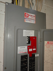 An open electrical panel with a generator interlock kit and startup instructions by Sherrill Company, LLC Electrical Contractors in Columbus, GA.
