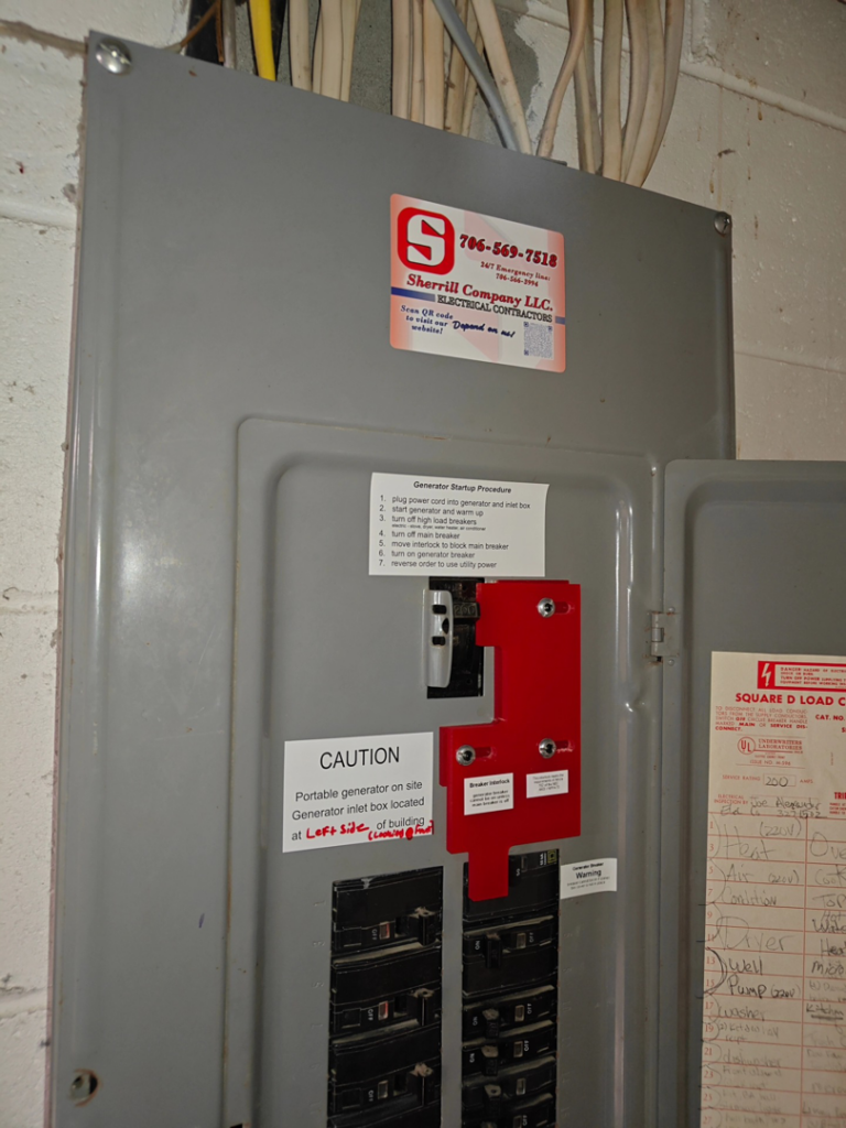 An open electrical panel with a generator interlock kit and startup instructions by Sherrill Company, LLC Electrical Contractors in Columbus, GA.