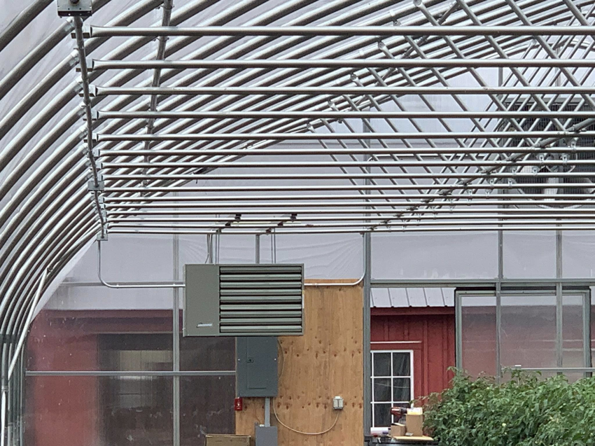 An electrical panel and HVAC unit with visible wiring in a greenhouse, installed by Hulett Electric & Father in Shaftsbury, VT.