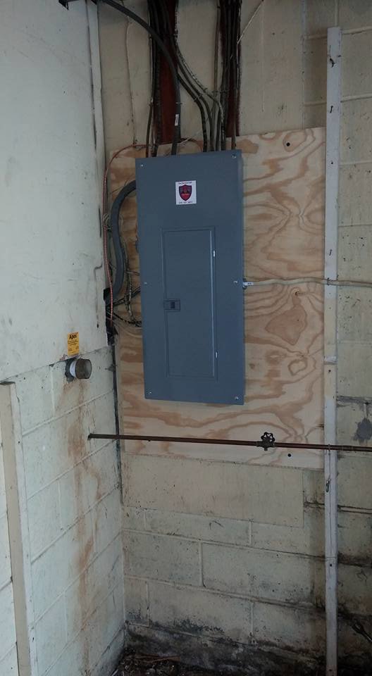 An electrical panel installed on a wooden board in a basement by Dragons Electric in Schenectady, NY