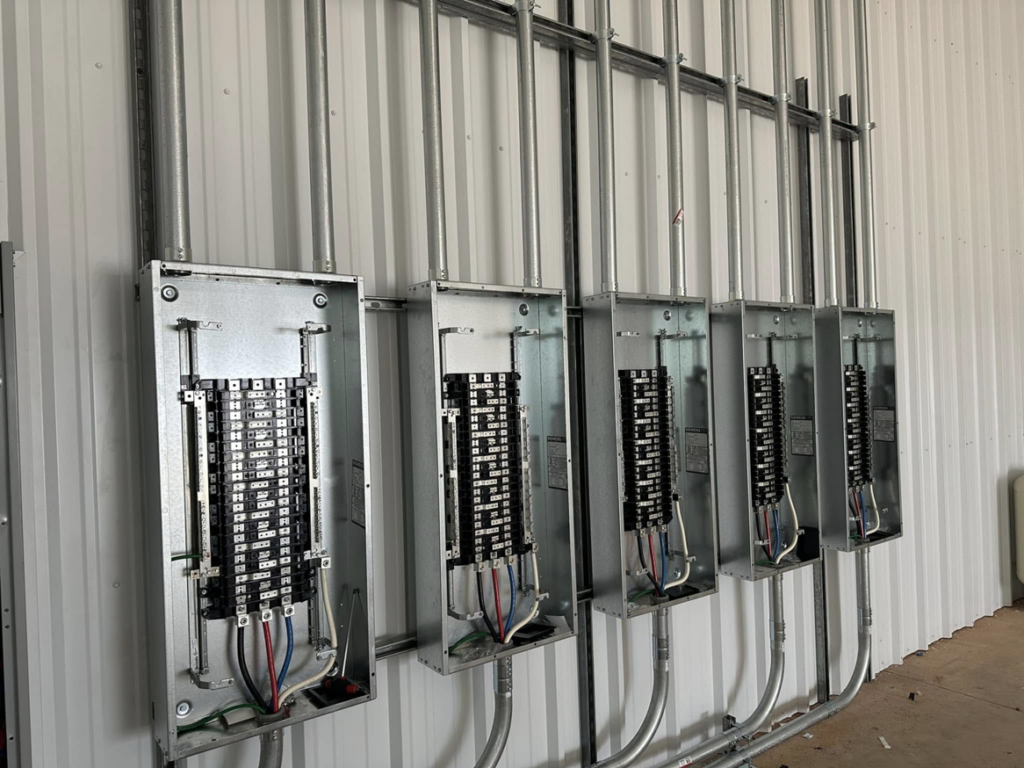 Multiple electrical panels and conduits installed on a wall inside a building by McLearen Electric in Piedmont, OK.