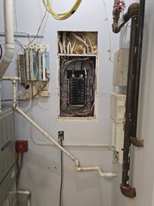 An open electrical panel with wiring and circuit breakers, showing an installation by DHJ Electric in Methuen, MA.