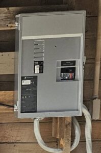 A newly installed electrical panel and main disconnect box on a wooden wall by Elite Electric Company in Melrose Park, IL
