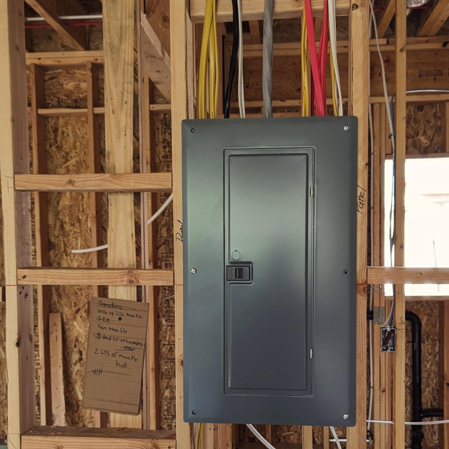 An electrical panel with its cover closed, installed in a wooden framed wall during construction by Lara Electric in Miami, FL.
