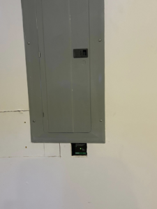 A gray electrical panel (breaker box) installed in a wall, showing professional electrical work by MLEC in Annapolis, MD