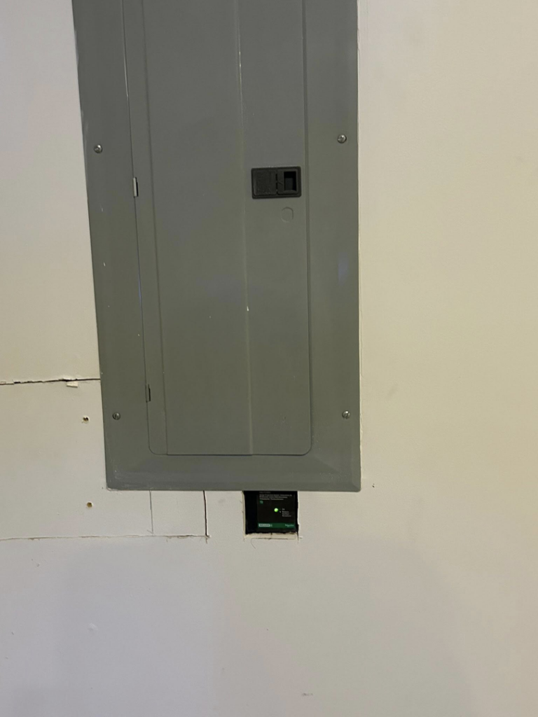 A gray electrical panel (breaker box) installed in a wall, showing professional electrical work by MLEC in Annapolis, MD