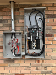 An outdoor electrical panel and meter base installation on a brick wall by Next Level Pros in Lakewood, CO.