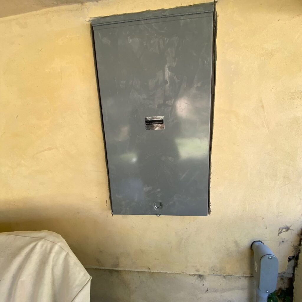 A closed electrical panel recessed into a yellow wall, indicating a completed installation by Prime Electric in Bellevue, WA.